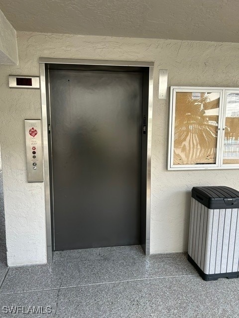 details with elevator, a textured wall, and radiator