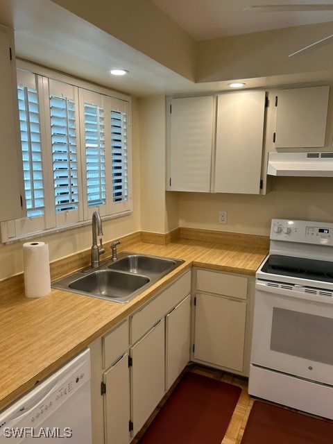kitchen featuring light countertops, white appliances, under cabinet range hood, white cabinetry, and a sink