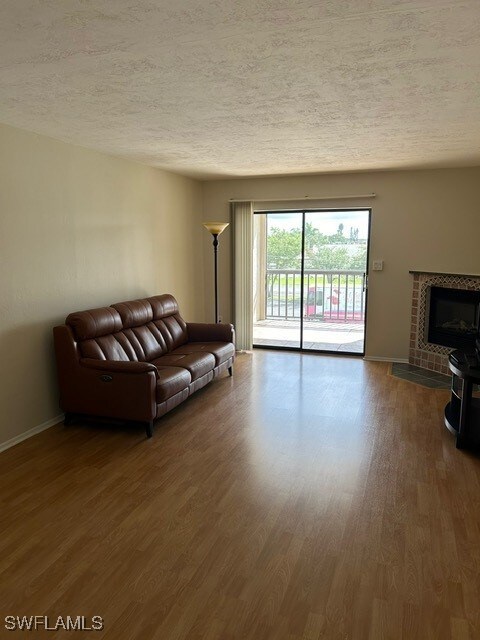 living area with baseboards, dark wood-style flooring, and a textured ceiling