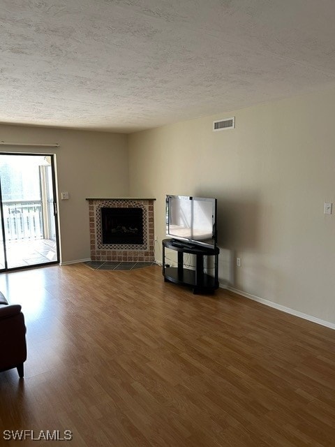 unfurnished living room with a textured ceiling, a tiled fireplace, and dark hardwood / wood-style flooring