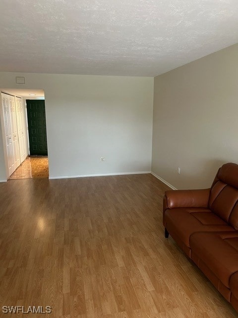 unfurnished living room with baseboards, light wood-style flooring, and a textured ceiling