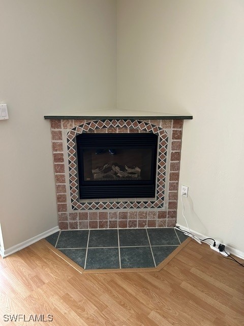 room details with a fireplace with flush hearth, baseboards, and wood finished floors