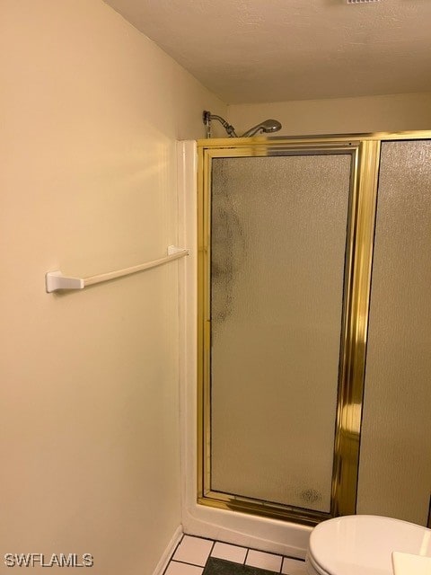 full bathroom with toilet, tile patterned flooring, and a shower stall