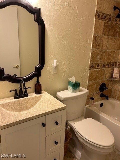 bathroom featuring  shower combination, toilet, vanity, and a textured wall