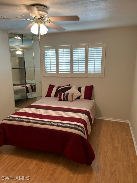 bedroom featuring multiple windows, light wood-style flooring, baseboards, and a ceiling fan