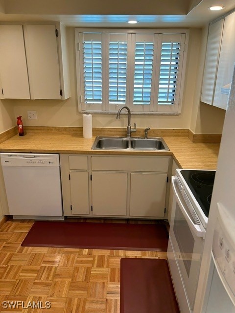 kitchen with white cabinets, white appliances, light parquet floors, and sink