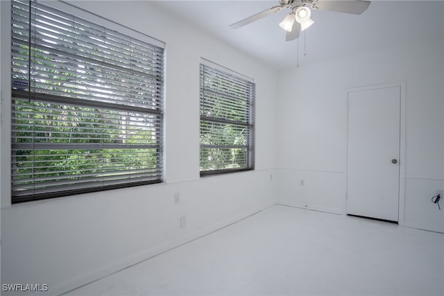 spare room featuring ceiling fan, a wealth of natural light, and concrete floors