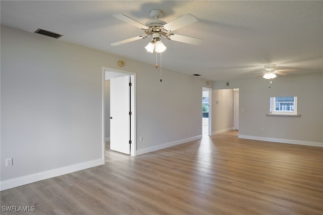 unfurnished room with a textured ceiling, ceiling fan, and light wood-type flooring