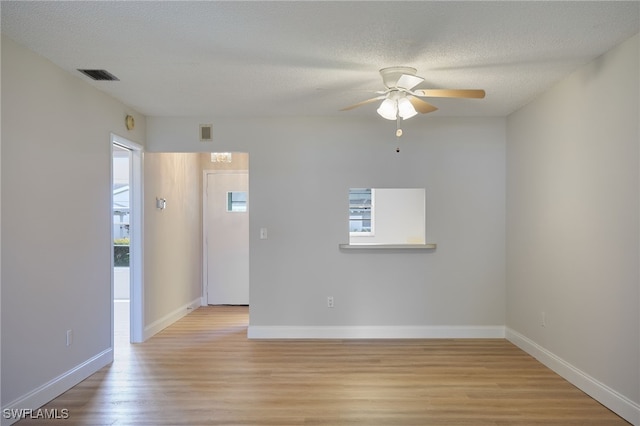 unfurnished room with light wood-type flooring, visible vents, and a textured ceiling