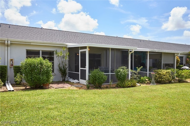 rear view of property with a sunroom, a shingled roof, a lawn, and stucco siding