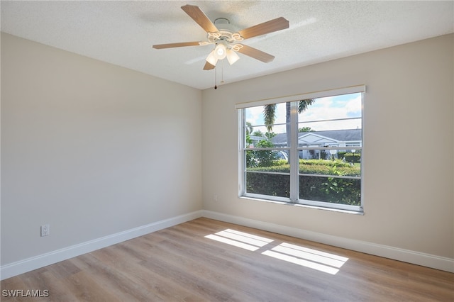 spare room featuring light wood-type flooring, ceiling fan, a textured ceiling, and baseboards