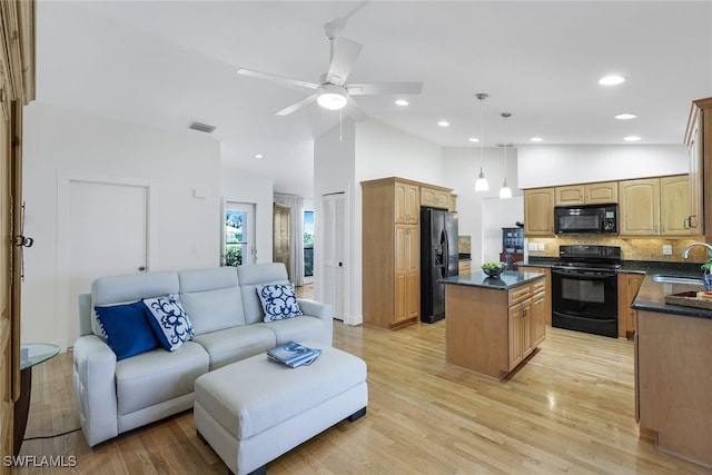 kitchen with light hardwood / wood-style floors, a kitchen island, pendant lighting, black appliances, and sink