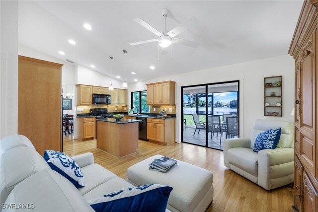 living room with light wood-type flooring, lofted ceiling, sink, and ceiling fan