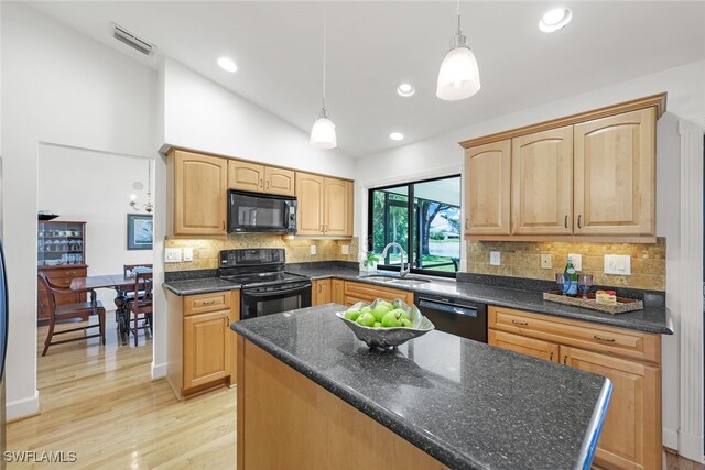 kitchen with sink, decorative light fixtures, black appliances, light wood-type flooring, and vaulted ceiling