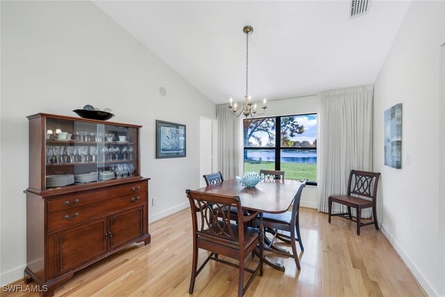 dining space with light wood-type flooring, a chandelier, and high vaulted ceiling