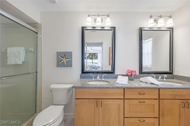 bathroom featuring a wealth of natural light, vanity, toilet, and an enclosed shower