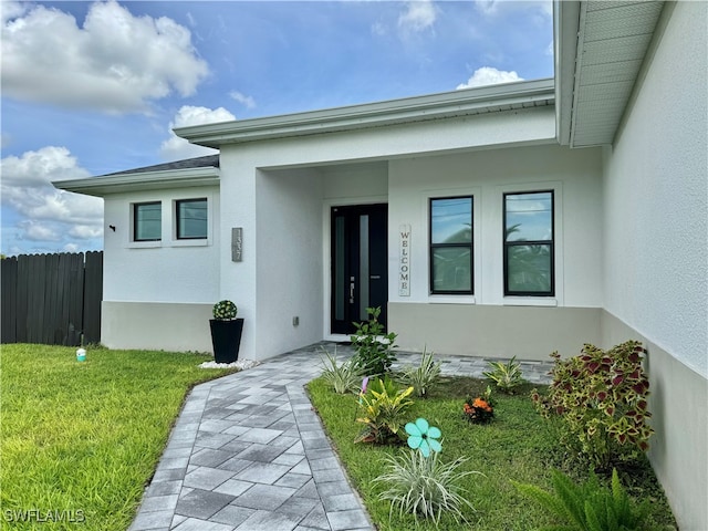 view of exterior entry with a yard