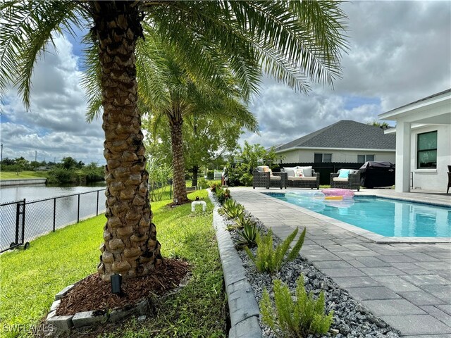 view of swimming pool featuring a patio area, a water view, a lawn, an outdoor hangout area, and area for grilling