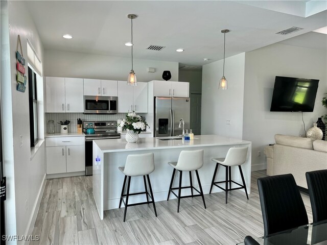 kitchen with decorative light fixtures, appliances with stainless steel finishes, and white cabinetry