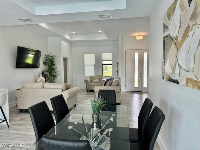 dining space featuring a tray ceiling and light hardwood / wood-style flooring