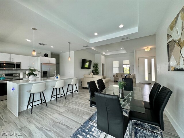 dining area with a raised ceiling and light hardwood / wood-style floors