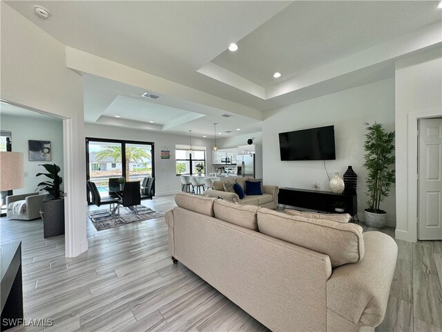 living room featuring a raised ceiling and light hardwood / wood-style flooring