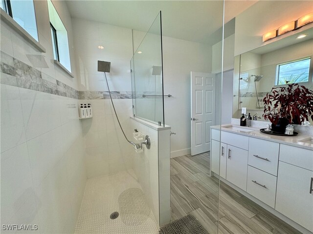 bathroom with wood-type flooring, a tile shower, and vanity