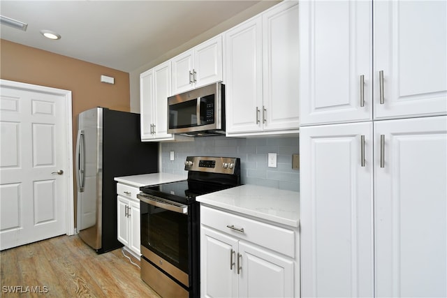 kitchen with light wood-type flooring, appliances with stainless steel finishes, white cabinetry, and tasteful backsplash