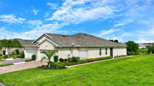 ranch-style house featuring a front yard, roof with shingles, stucco siding, a garage, and decorative driveway