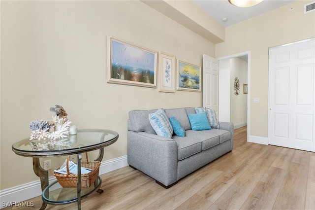 living room with light wood-style flooring, visible vents, and baseboards