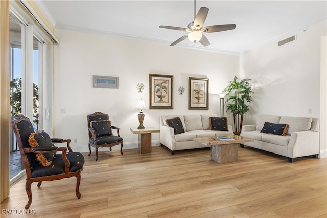 living area with ornamental molding, visible vents, and light wood-style floors