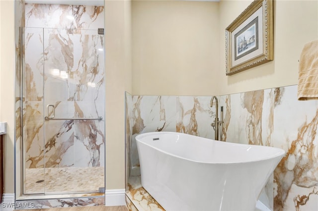 bathroom featuring a marble finish shower and a freestanding bath