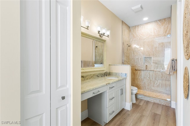 full bath with a closet, toilet, a stall shower, vanity, and wood finished floors