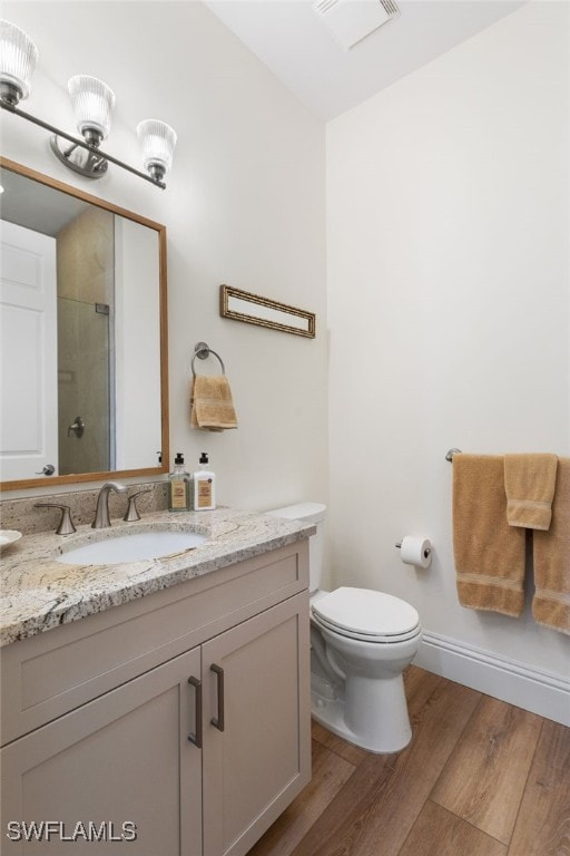 bathroom with a shower with door, visible vents, toilet, vanity, and wood finished floors