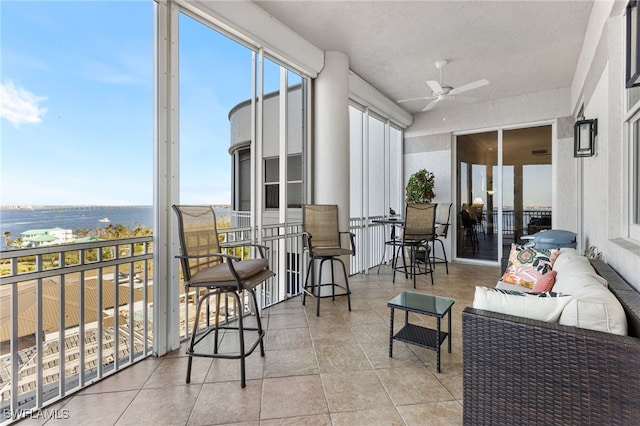 sunroom / solarium with ceiling fan and a water view