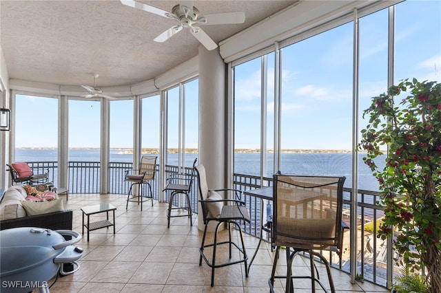 sunroom featuring a water view and ceiling fan