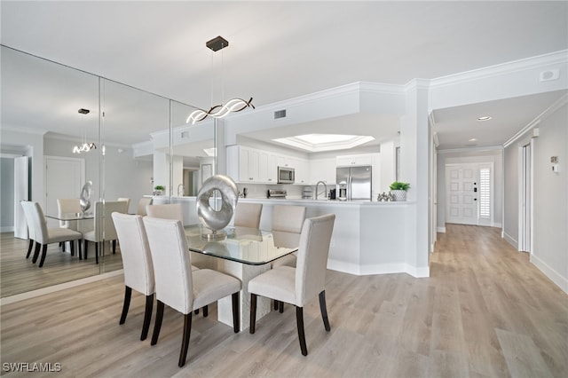 dining area featuring light wood-type flooring, crown molding, sink, and a notable chandelier