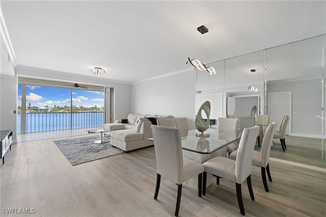 dining area featuring a water view, an inviting chandelier, crown molding, and light hardwood / wood-style flooring