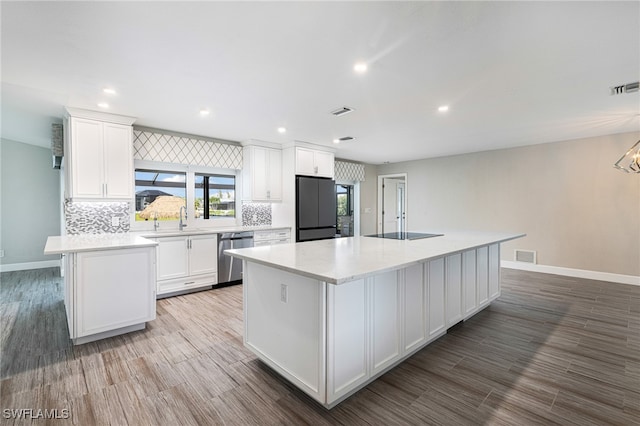 kitchen with refrigerator, white cabinets, a kitchen island, and wood-type flooring