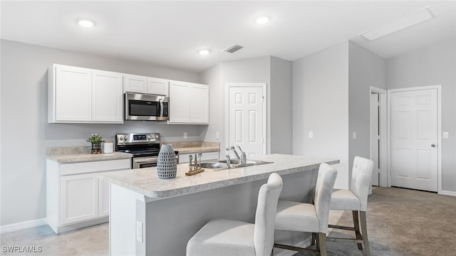 kitchen featuring sink, white cabinetry, stainless steel appliances, and an island with sink