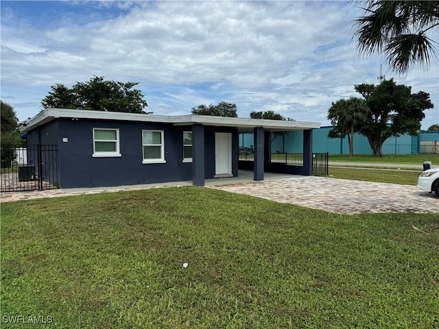 view of front of property featuring stucco siding, an attached carport, a front yard, and fence