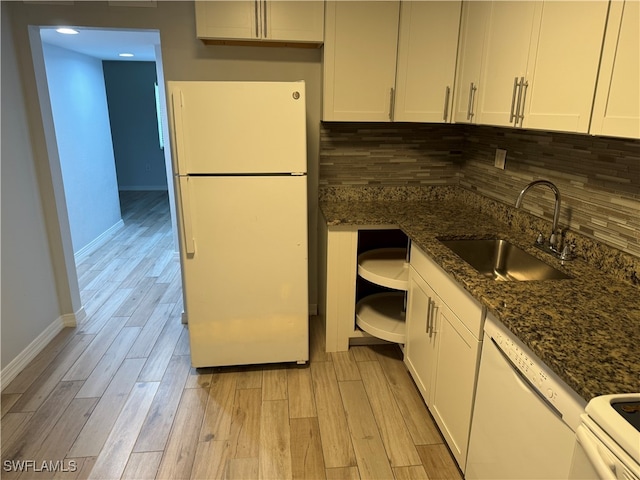 kitchen featuring white cabinets, light wood-type flooring, white appliances, sink, and dark stone counters