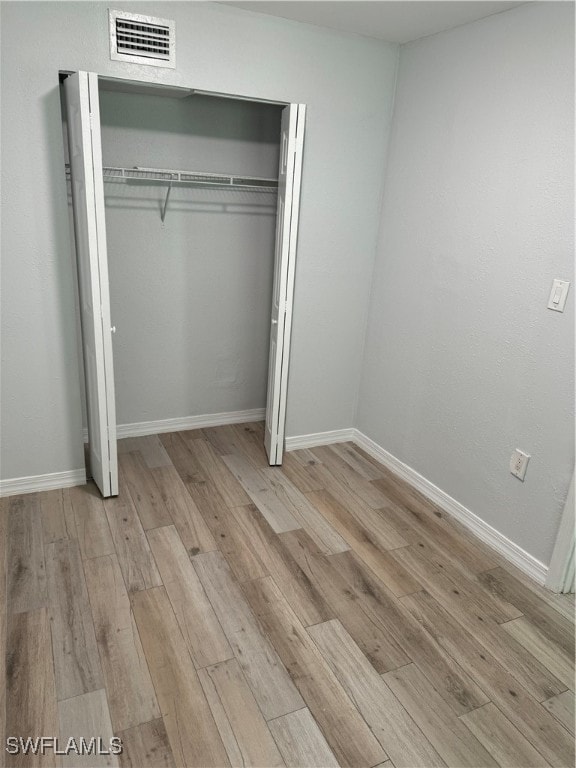 unfurnished bedroom featuring light wood-type flooring and a closet