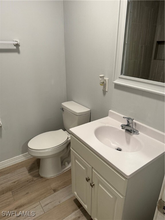 bathroom with vanity, toilet, and hardwood / wood-style floors