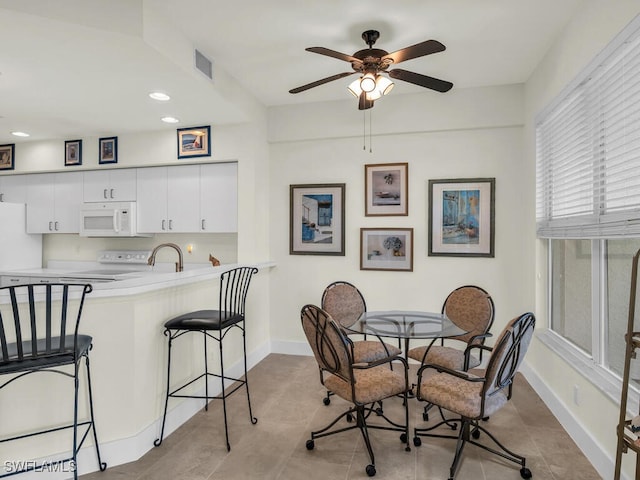 tiled dining area featuring ceiling fan and sink