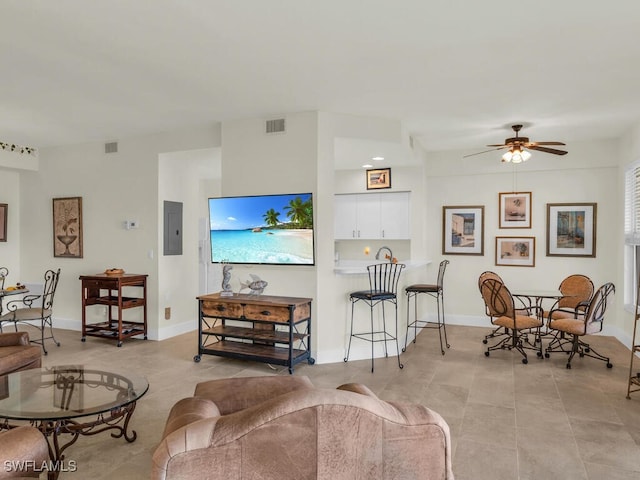 tiled living room featuring ceiling fan and electric panel