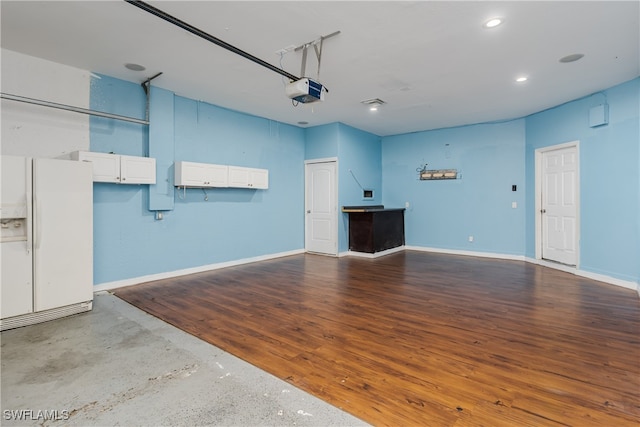 garage featuring a garage door opener and white fridge with ice dispenser