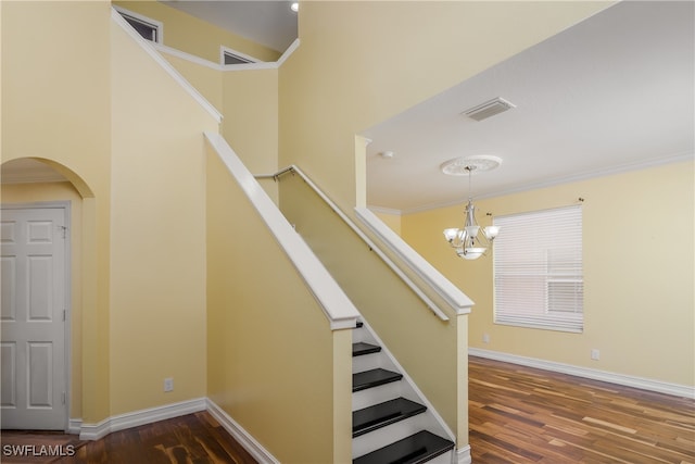 stairway featuring wood-type flooring, a notable chandelier, and ornamental molding