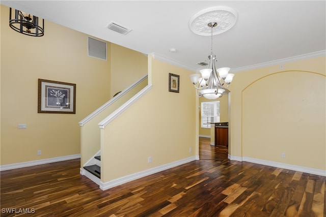 spare room featuring an inviting chandelier, dark hardwood / wood-style flooring, and ornamental molding