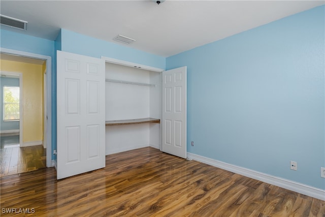 unfurnished bedroom featuring a closet and dark hardwood / wood-style flooring